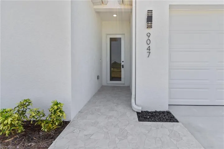 Doorway to property featuring stucco siding and a garage