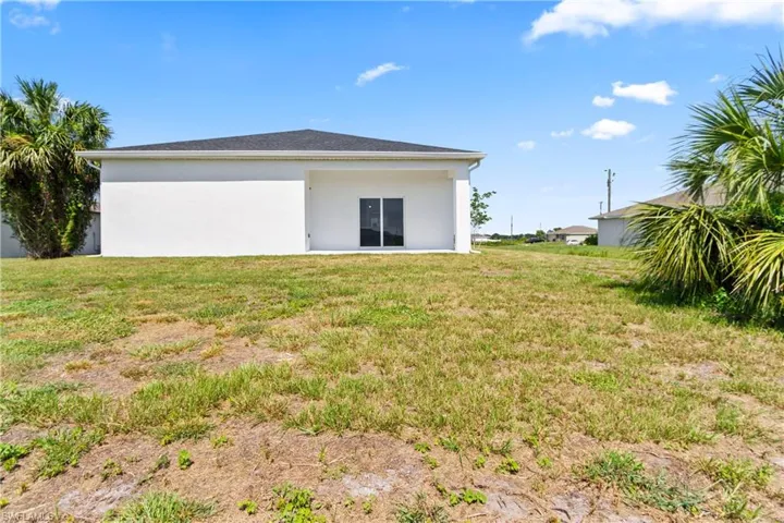 Back of property with stucco siding and a lawn