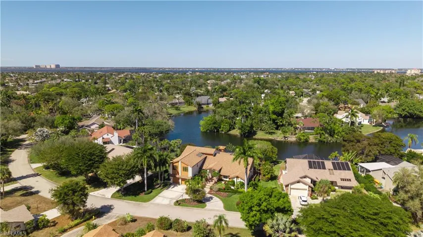 Aerial view of residential area featuring a tree filled landscape and a large body of water