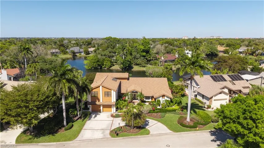 Aerial view of residential area featuring a tree filled landscape and a nearby body of water