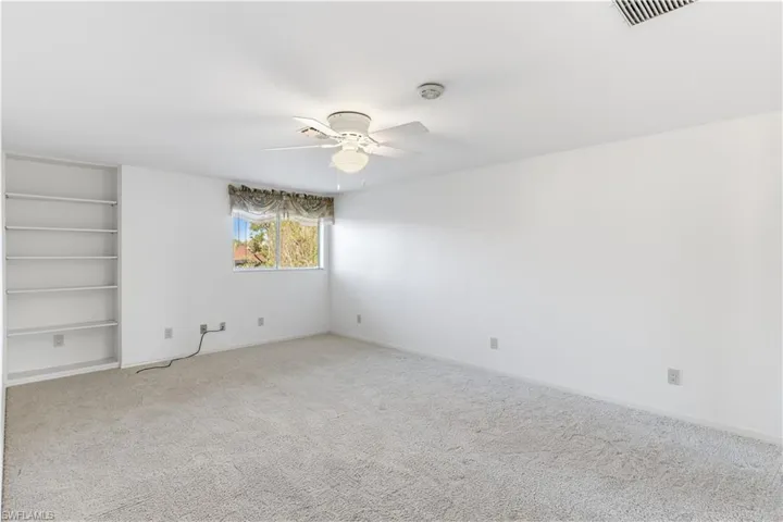upstairs Bedroom with ceiling fan, built in shelves, and carpet flooring