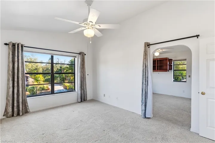 upstairs Bedroom featuring ceiling fan, vaulted ceiling, and arched walkways