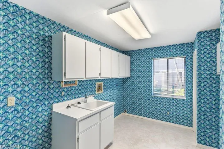 Laundry room with hookup for a washing machine, wallpapered walls, and light tile patterned floors