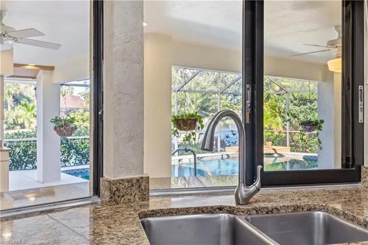 Kitchen view of a ceiling fan, a sunroom, and light stone countertops