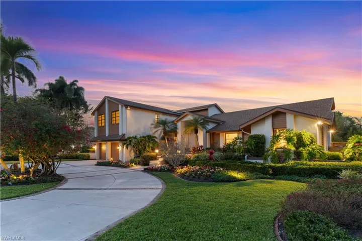 View of front of property with a yard, stucco siding, and curved driveway