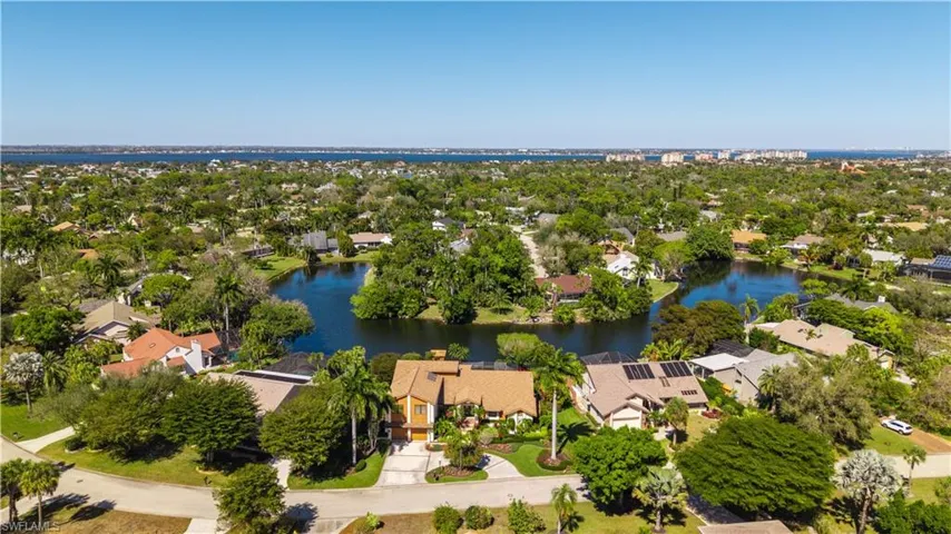 Aerial view of residential area featuring a tree filled landscape and a nearby body of water