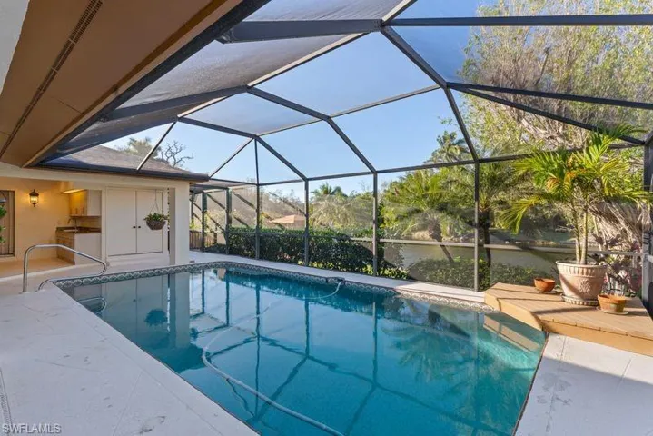 Outdoor pool featuring a sunroom, glass enclosure, and a patio