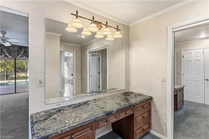 Bathroom with dark carpet, a textured wall, ornamental molding, vanity, and ceiling fan