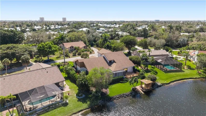 Aerial perspective of suburban area with a nearby body of water and a tree filled landscape