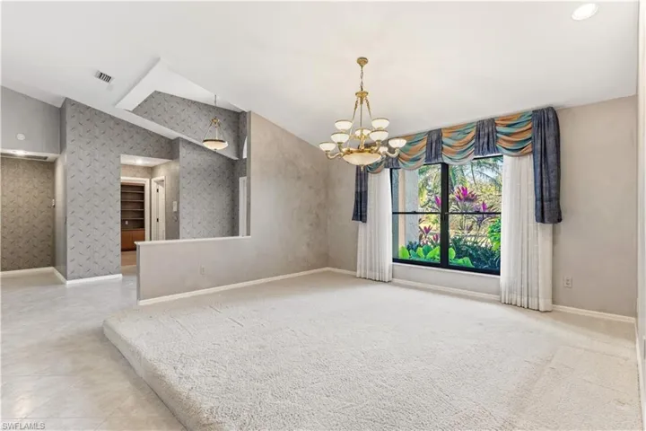 Unfurnished room with vaulted ceiling, wallpapered walls, and a chandelier