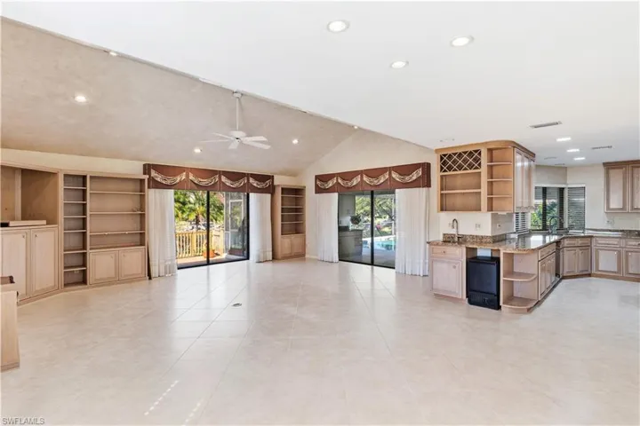 Kitchen with open shelves, vaulted ceiling, dark stone countertops, plenty of natural light, and recessed lighting