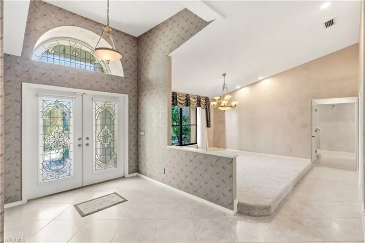 Entrance foyer with french doors, lofted ceiling, light tile patterned floors, and hanging lights