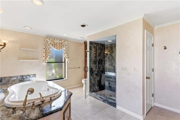 Master Bathroom featuring crown molding, a garden tub, a marble finish shower, and light tile patterned floors