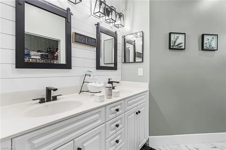 Full bath featuring double vanity and baseboards