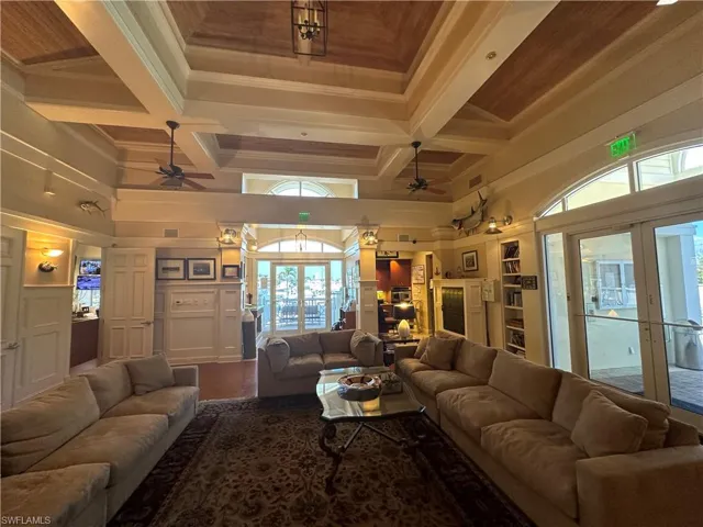 Living room featuring a ceiling fan, coffered ceiling, a high ceiling, plenty of natural light, and crown molding