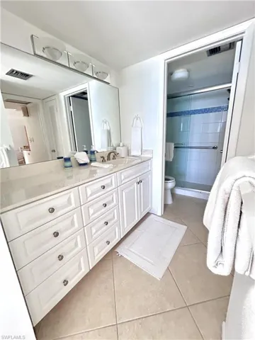Full bath with vanity, light tile patterned floors, and a stall shower