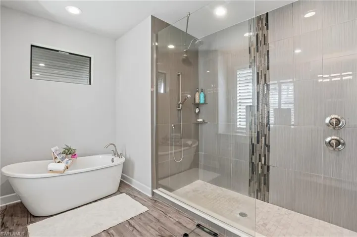 Full bath featuring a freestanding tub, a walk in shower, wood finished floors, and recessed lighting