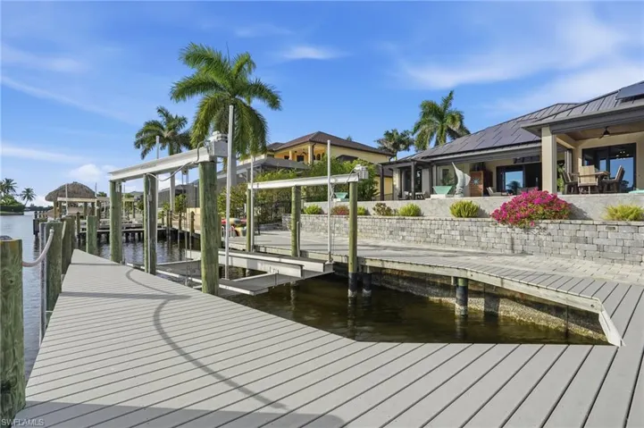 Dock area featuring a water view, boat lift, and a patio