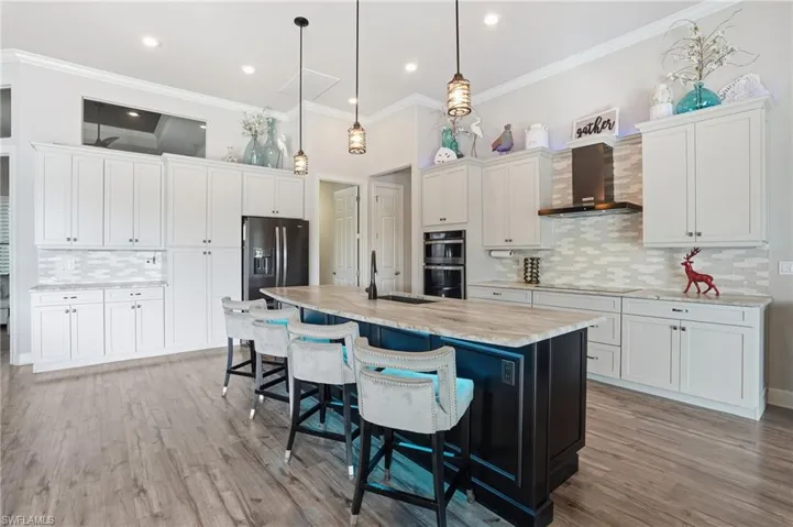 Kitchen featuring tasteful backsplash, decorative light fixtures, white cabinetry, a kitchen breakfast bar, and crown molding