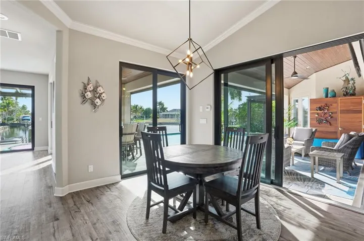 Dining space with a water view, ornamental molding, wood finished floors, lofted ceiling, and a chandelier
