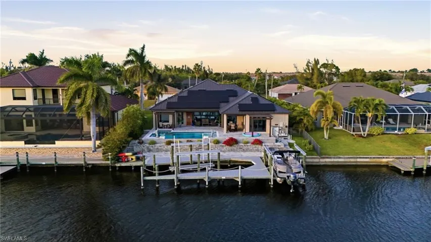 Dock with a water view, a patio area, boat lift, and an outdoor pool