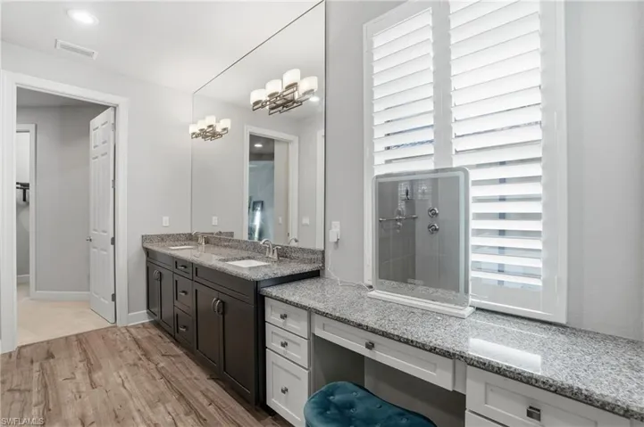 Bathroom with double vanity, light wood-type flooring, recessed lighting, and a chandelier