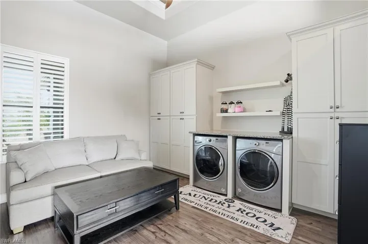 Laundry area featuring washer and dryer, dark wood-type flooring, built-in cabinets, and flex space.