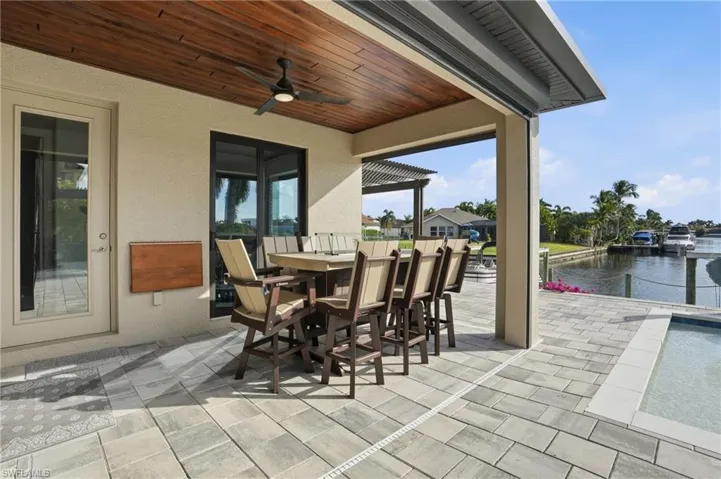 View of patio featuring outdoor dining area, a ceiling fan, and a water view