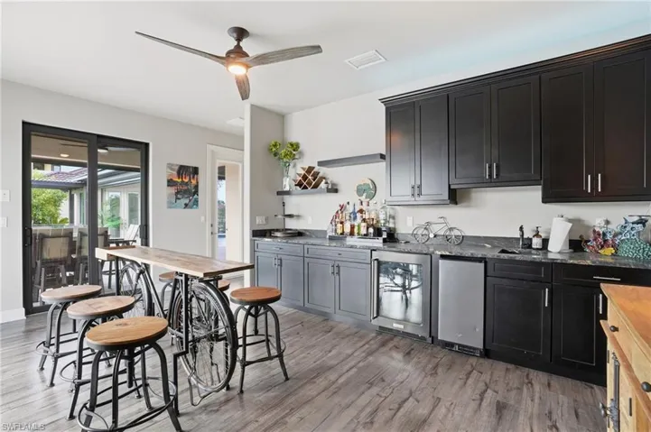 Media room with built-in cabinets, a beverage refrigerator, an ice maker, and a wet bar.