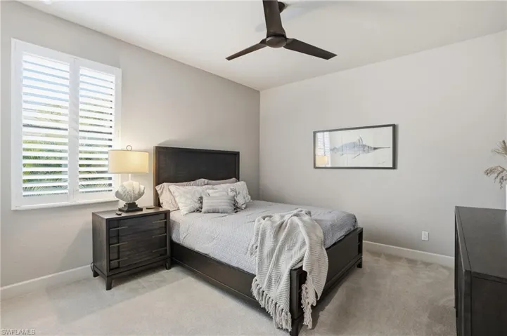 Carpeted bedroom with a ceiling fan and baseboards