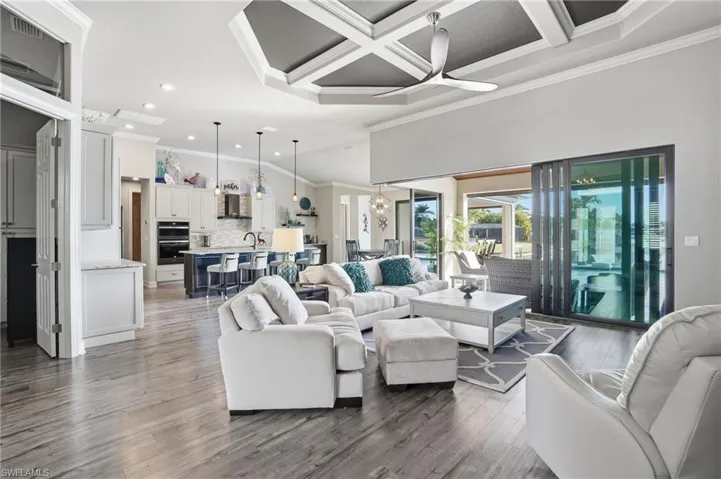 Living room featuring ornamental molding, coffered ceiling, light wood-style flooring, beam ceiling, and recessed lighting
