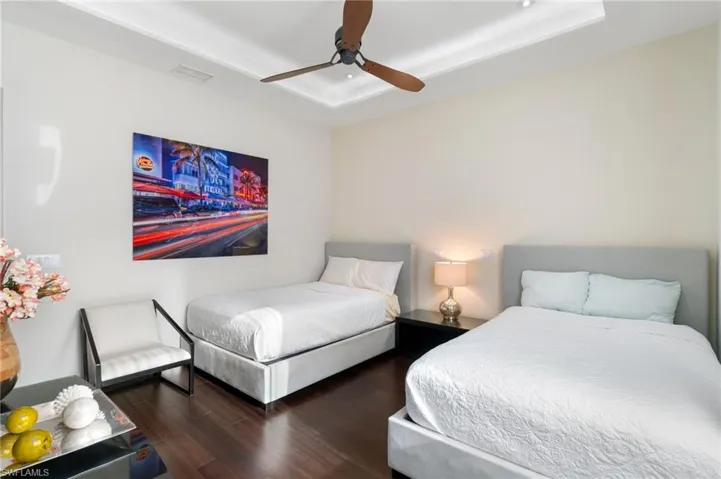 Bedroom with a tray ceiling, ceiling fan, and dark wood-type flooring