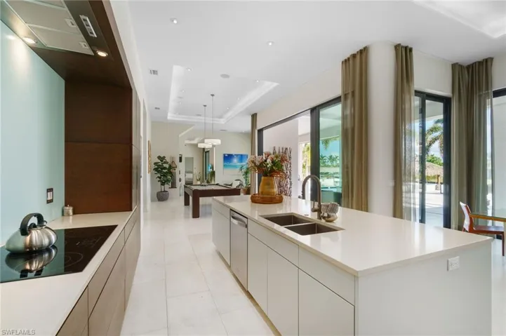 Kitchen with a kitchen island with sink, white cabinets, black electric stovetop, a raised ceiling, and sink