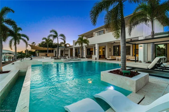 Pool at dusk with a patio area and ceiling fan