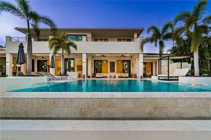 Pool at dusk with outdoor lounge area, ceiling fan, and a patio