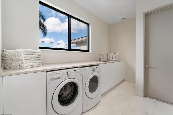 Laundry room featuring cabinets, separate washer and dryer, sink, and light tile patterned floors
