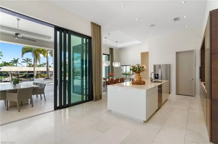 Kitchen with ceiling fan, sink, a center island with sink, white cabinets, and appliances with stainless steel finishes