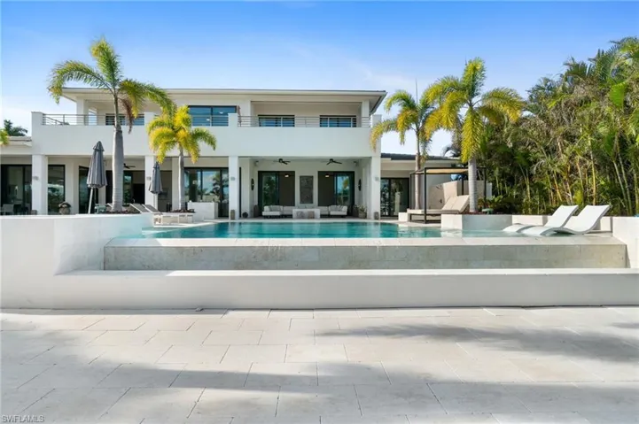 Back of house with a balcony, a pool with hot tub, an outdoor living space, ceiling fan, and a patio