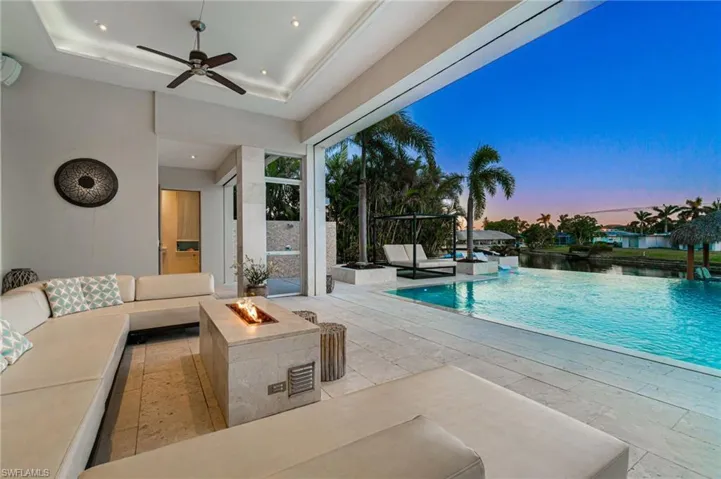 Pool at dusk featuring an outdoor living space with a fire pit, a patio area, and ceiling fan