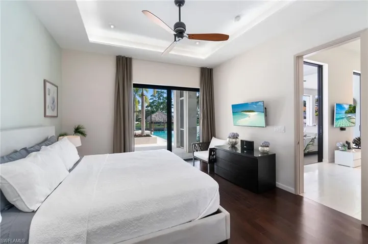 Bedroom featuring access to exterior, dark hardwood / wood-style flooring, a raised ceiling, and ceiling fan