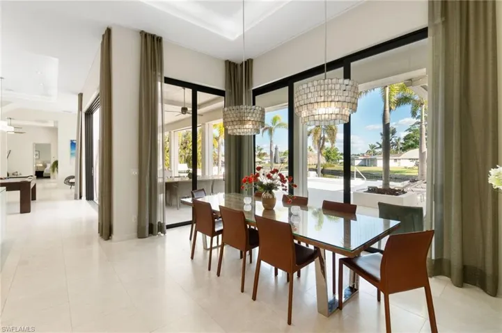 Tiled dining area with a tray ceiling and ceiling fan with notable chandelier