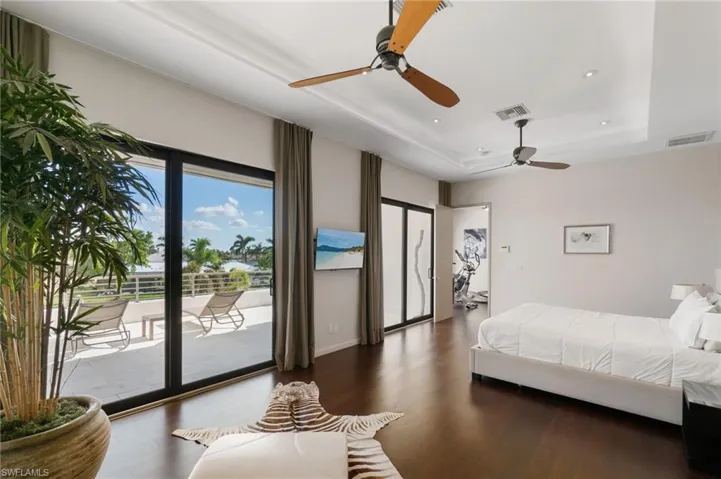Bedroom with access to outside, ceiling fan, a tray ceiling, and dark hardwood / wood-style floors