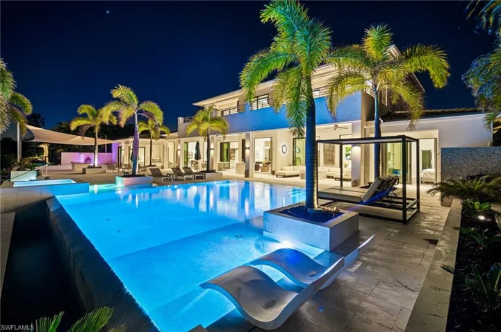 Pool at twilight with outdoor lounge area, a patio, and a hot tub