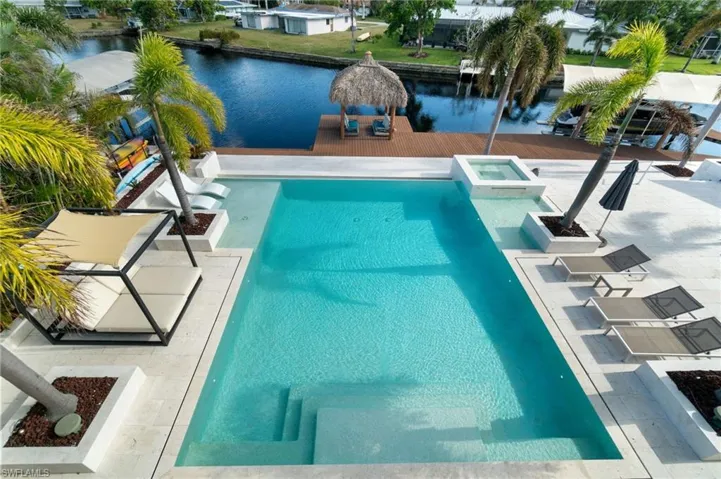View of swimming pool with a patio area, an in ground hot tub, and a water view