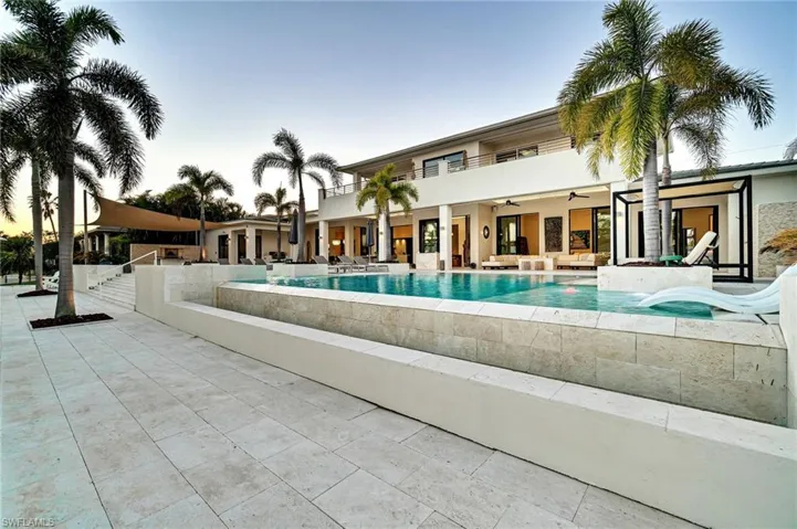 Pool at dusk with ceiling fan, an outdoor hangout area, and a patio