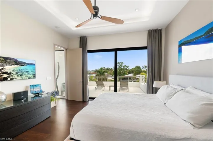 Bedroom featuring access to outside, a raised ceiling, ceiling fan, and multiple windows