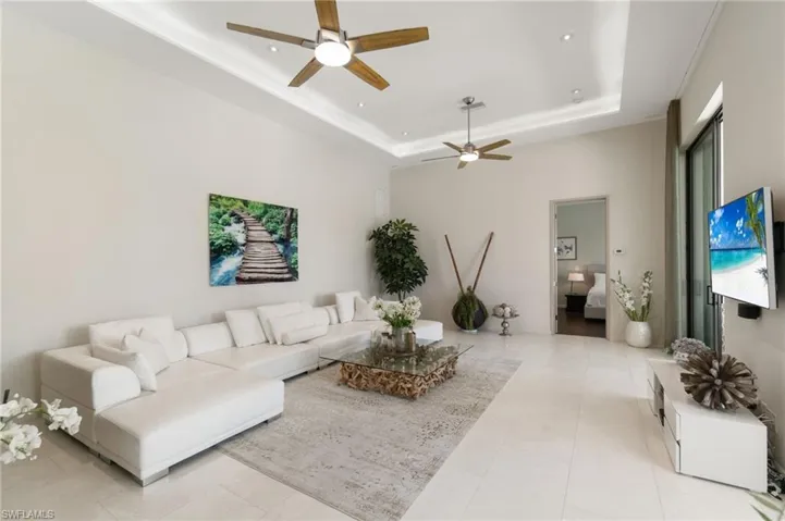 Tiled living room with ceiling fan and a tray ceiling