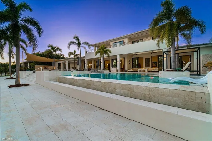 Pool at dusk featuring ceiling fan, a patio area, and an outdoor hangout area