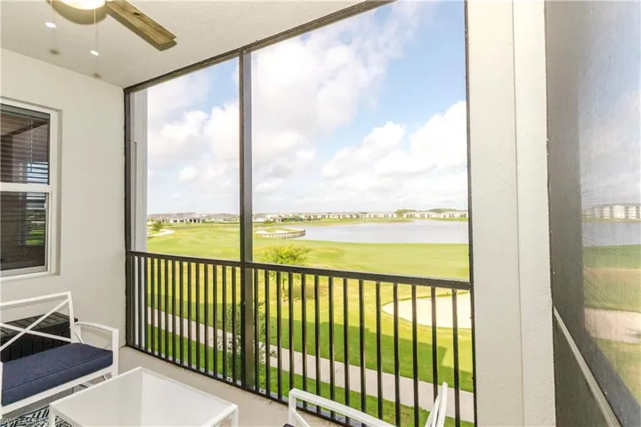 Sunroom with a ceiling fan, view of golf course, and a water view