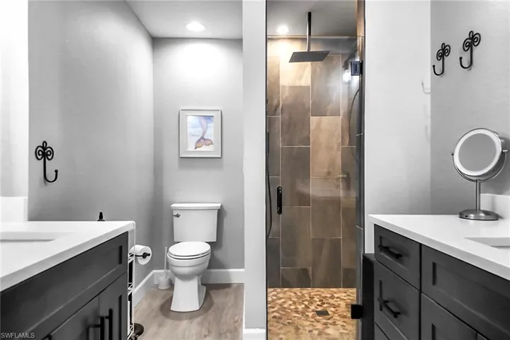 Completely remodeled primary bath with modern separate vanities, walk-in shower, and upgraded light fixtures.
